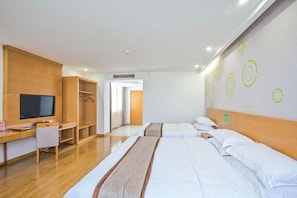 Ein Hotelzimmer mit Schreibtisch aus Holz, Fernseher, Kleiderschrank und zwei Betten mit weißer Bettwäsche.
