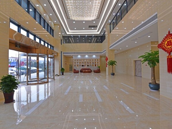 A spacious lobby with a glass entrance, a reception desk, and a chandelier.