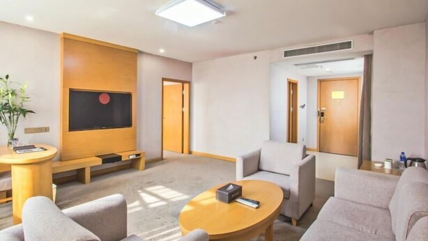 A modern hotel room with a seating area, a flat-screen TV, a coffee table, and a sofa. - Greentree Inn Tongxiang Chongfuzhen World Fur Cent (Jiaxing)