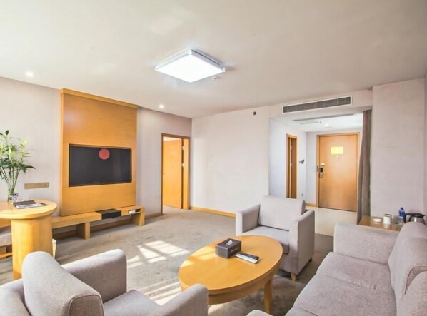 A modern hotel room with a seating area, a flat-screen TV, a coffee table, and a sofa. - Greentree Inn Tongxiang Chongfuzhen World Fur Cent (Jiaxing)