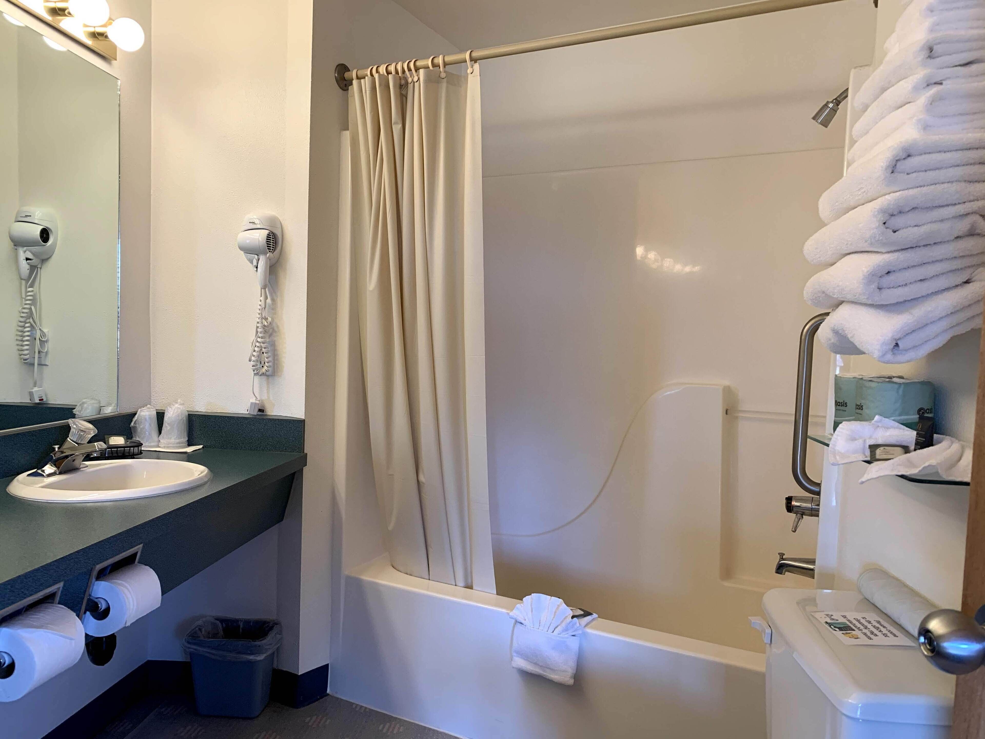 A bathroom with a sink, towel rack, shower curtain, and toilet.