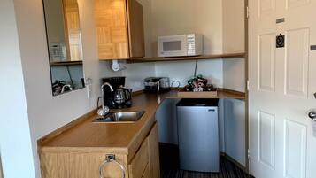 A compact kitchenette with a sink, a coffee maker, a microwave, and a small refrigerator.