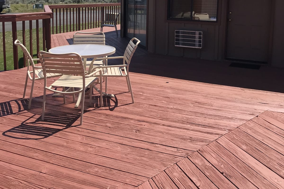 A wooden deck with a table and chairs, overlooking a mountainous landscape.