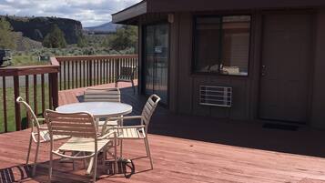 Una terraza de madera con una mesa y sillas, con vistas a un paisaje montañoso.