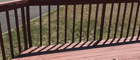 A wooden deck with a metal railing and a metal chair.