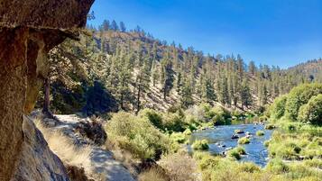 Un paisaje natural con un río, terreno rocoso y un cielo azul despejado.