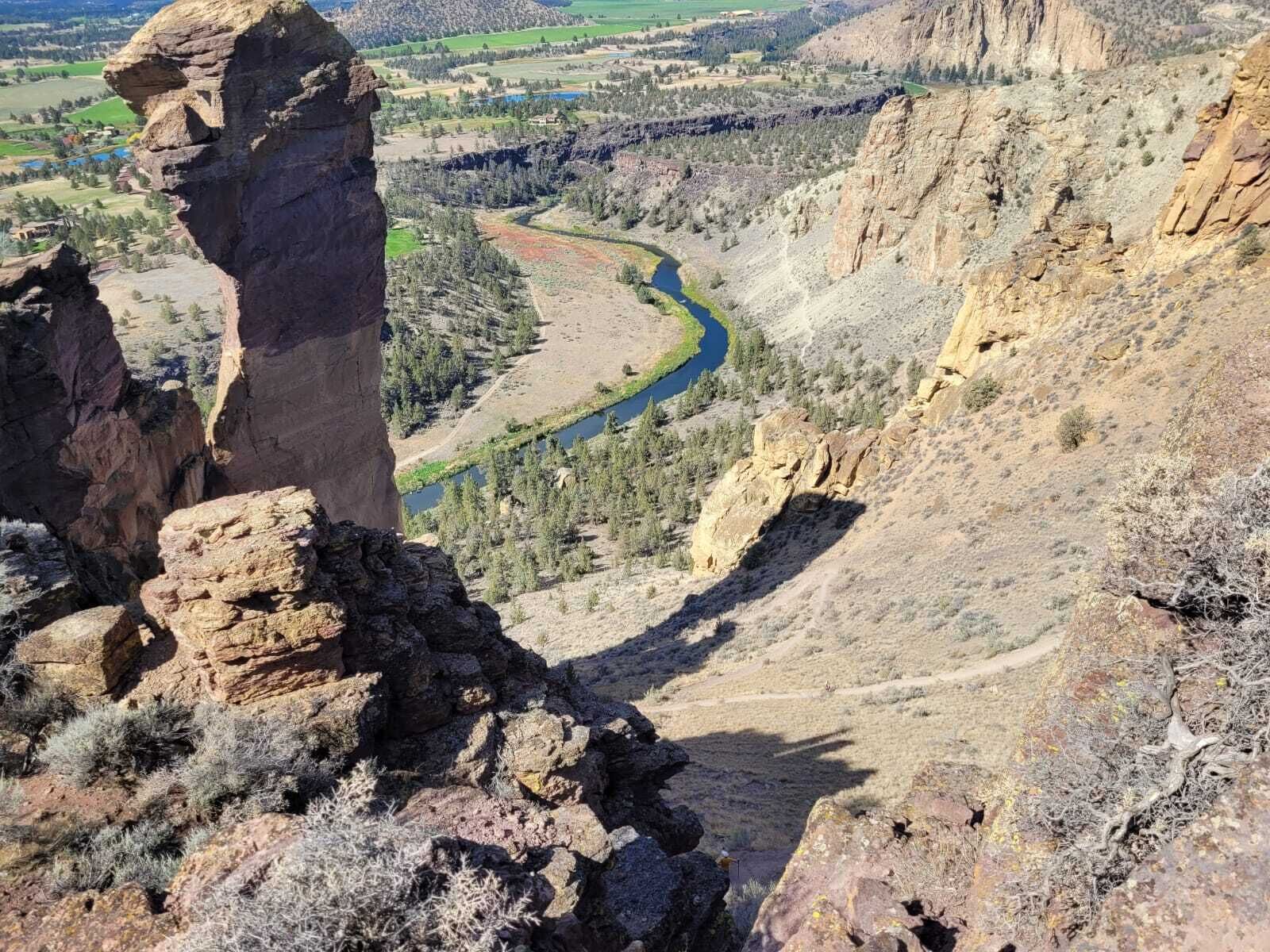 Un canyon avec une rivière, un terrain rocheux et une végétation clairsemée.