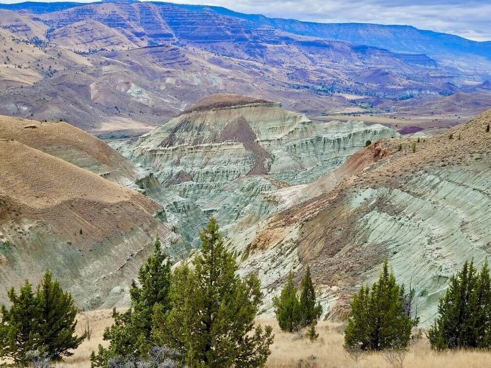 Een bergachtig landschap met gelaagde rotsformaties en schaarse begroeiing.
