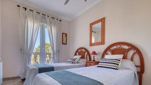A hotel room with two beds, a balcony, a ceiling fan, a mirror, and a window with curtains. - Alqueria Sol by Interhome (Dénia)