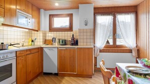 A kitchen with wooden cabinets, a microwave, a stove, and a window with curtains.