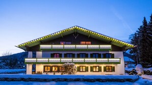 A two-story building with a sloped roof, multiple windows, and a snow-covered landscape.
