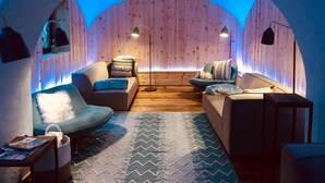 A cozy room with wooden walls, a patterned rug, and two sofas with pillows.