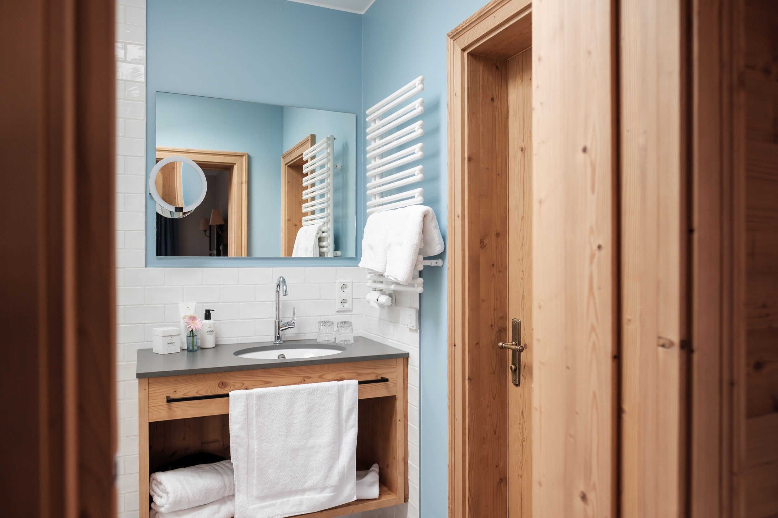 A bathroom with a wooden vanity, a mirror, a towel rack, and a sink.