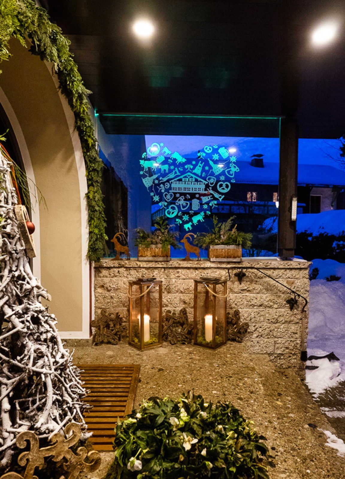 Un espace extérieur aménagé avec un mur en pierre, des lanternes et un sapin de Noël.