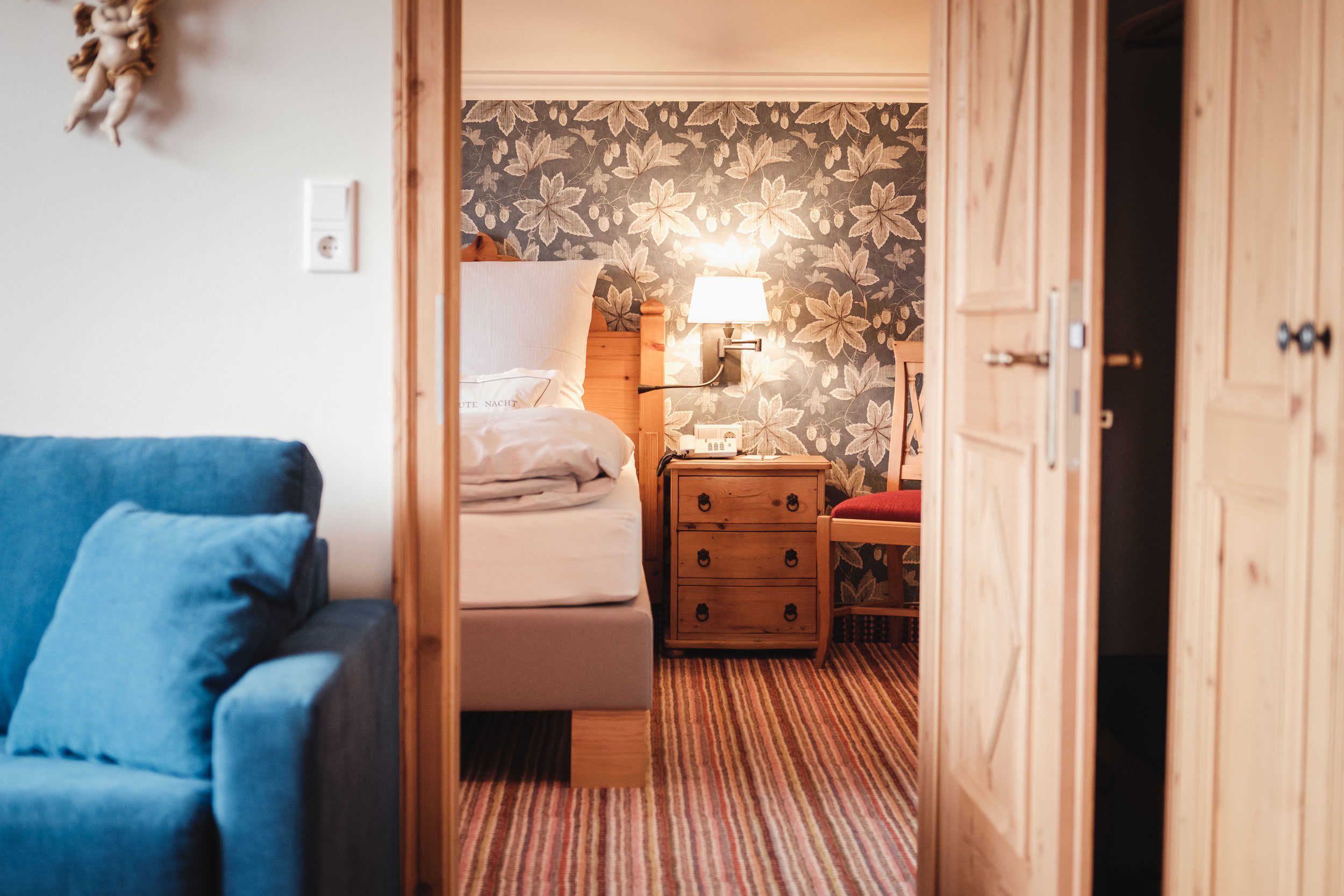A bedroom with a bed, bedside table, lamp, and a blue armchair.