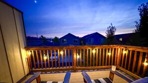 Eine Holzterrasse mit zwei gestreiften Stühlen und Lichterketten.