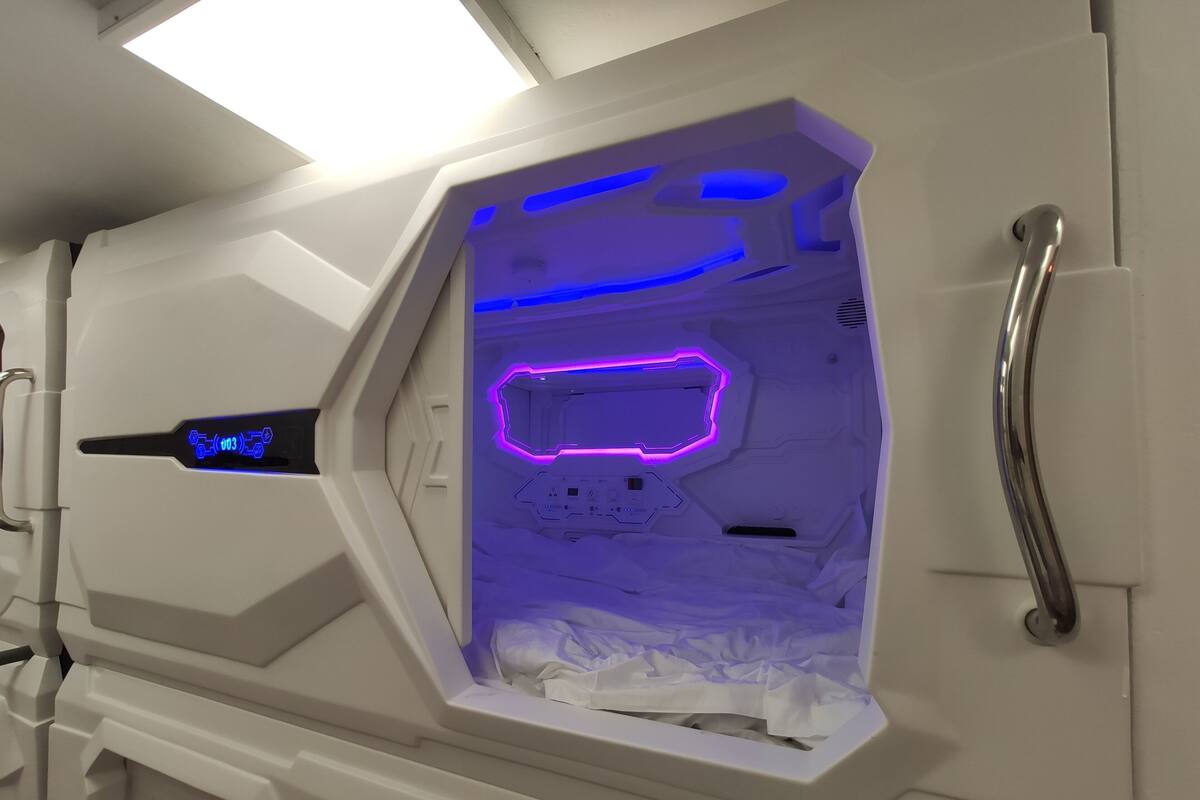 Ein Zimmer mit weißer Einrichtung, einem Metallgriff und einem neonbeleuchteten geometrischen Wandbild.