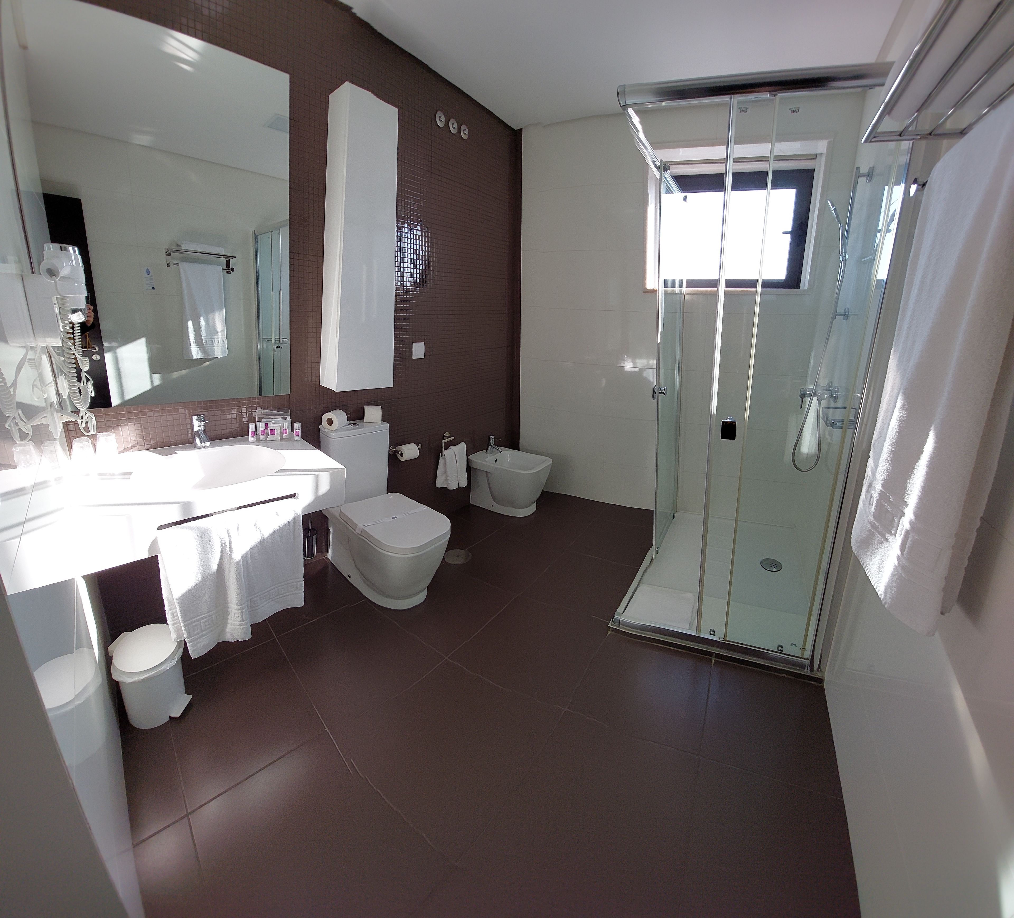 A modern bathroom with a glass-enclosed shower, a large mirror, and a dual sink vanity.