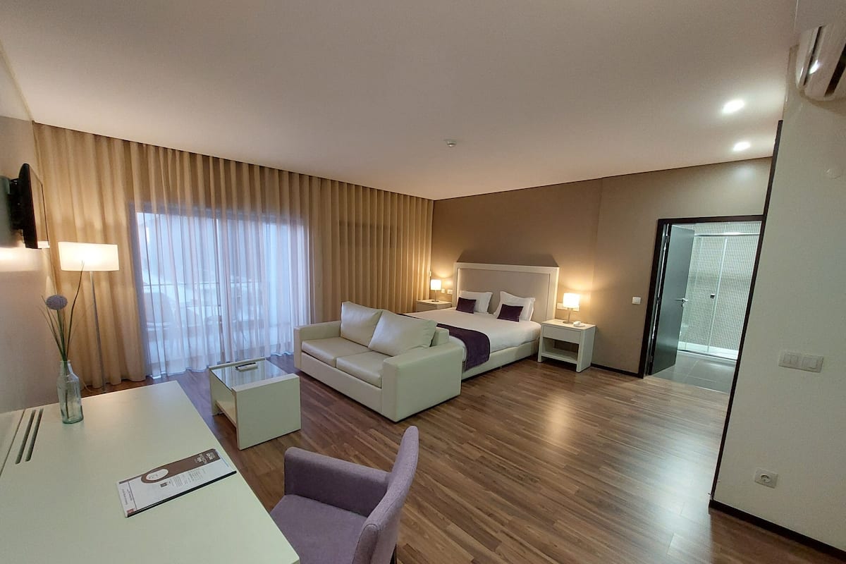 Una habitación de hotel moderna con cama, sofá, escritorio y una silla.