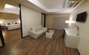Una habitación de hotel moderna con una cama, un sofá, un escritorio y un televisor.