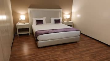Un dormitorio con una cama, dos mesitas de noche y suelo de madera.