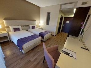 Una habitación de hotel con dos camas, un escritorio, una silla y una mesita de noche.