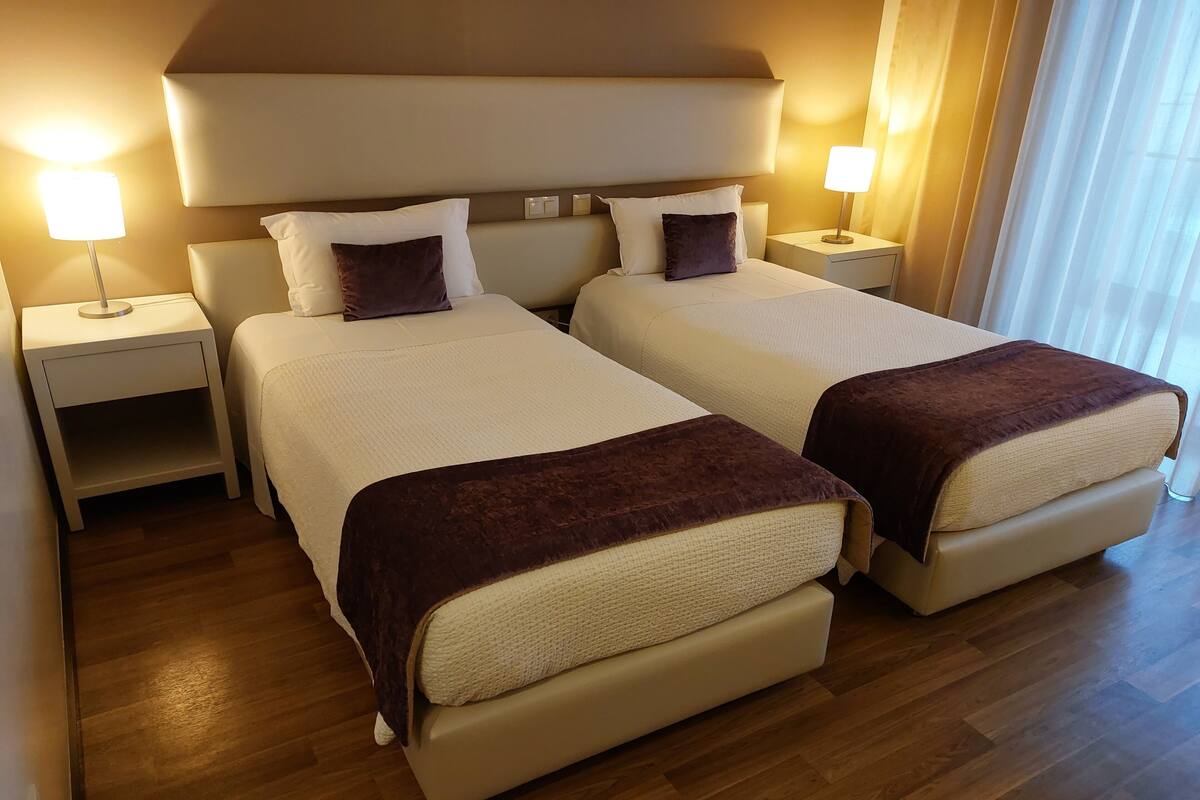 Una habitación de hotel con dos camas, mesitas de noche y lámparas.