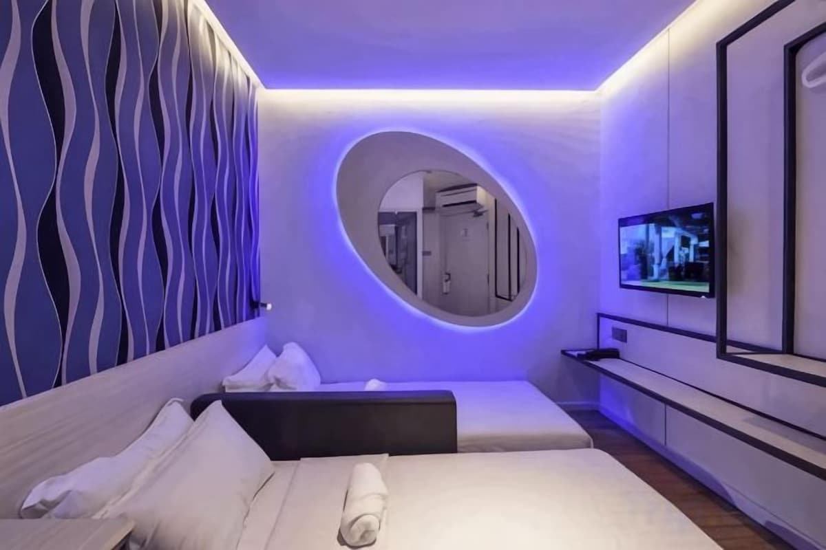 Een moderne hotelkamer met een bed, een televisie en een bijzonder wandontwerp.