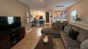 A living room with a sectional sofa, a coffee table, a TV, and a ceiling fan. - Oakwater, 3 bedrooms - The nearest resort from Disney! (Kissimmee)