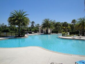 Piscina com espreguiçadeiras e palmeiras.
