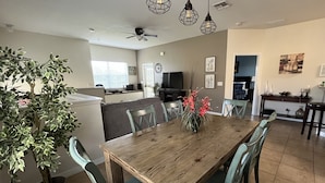 A dining area with a wooden table, green chairs, and a potted plant. - Oakwater, 3 bedrooms - The nearest resort from Disney! (Kissimmee)