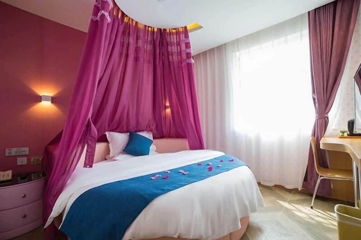 A bedroom with a bed, a desk, and a chair.