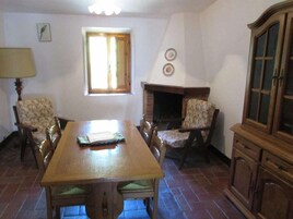Un comedor con una mesa de madera, dos sillas, una chimenea y un armario.