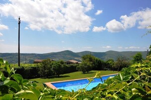 Una piscina rodeada de follaje y colinas al fondo.