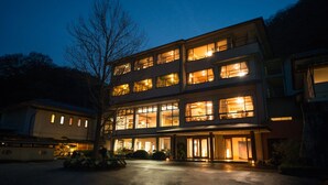 A multi-story hotel with a central courtyard, large windows on each floor, and a well-lit entrance. - Hotel Hanaya (Achi)
