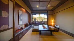 A traditional Japanese-style room with tatami flooring, a low table, and a view of the outdoors. - Hotel Hanaya (Achi)