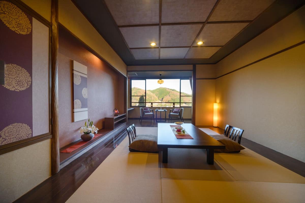 A traditional Japanese-style room with tatami flooring, a low table, and a view of the outdoors.