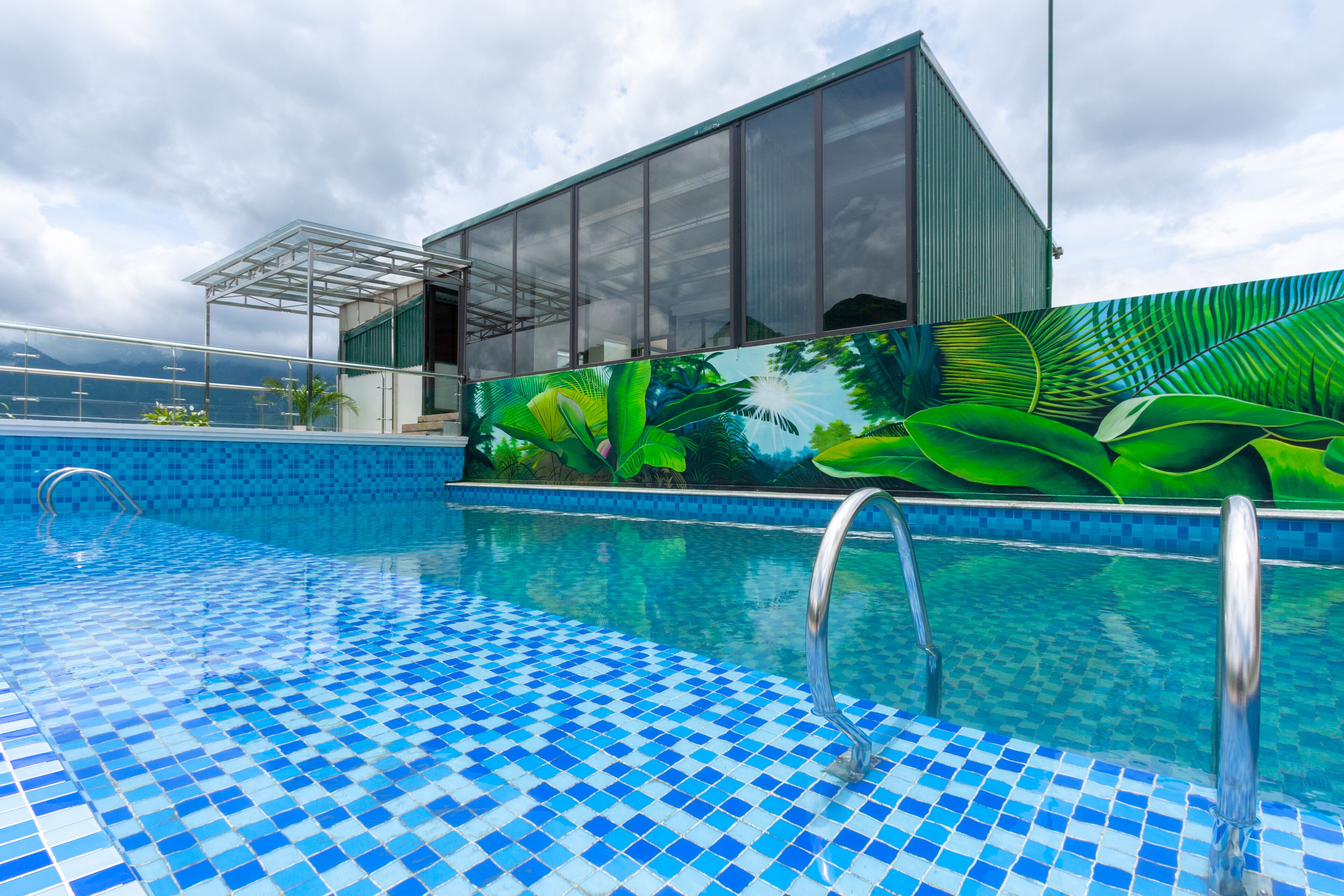 A swimming pool with blue mosaic tiles and a glass enclosure.