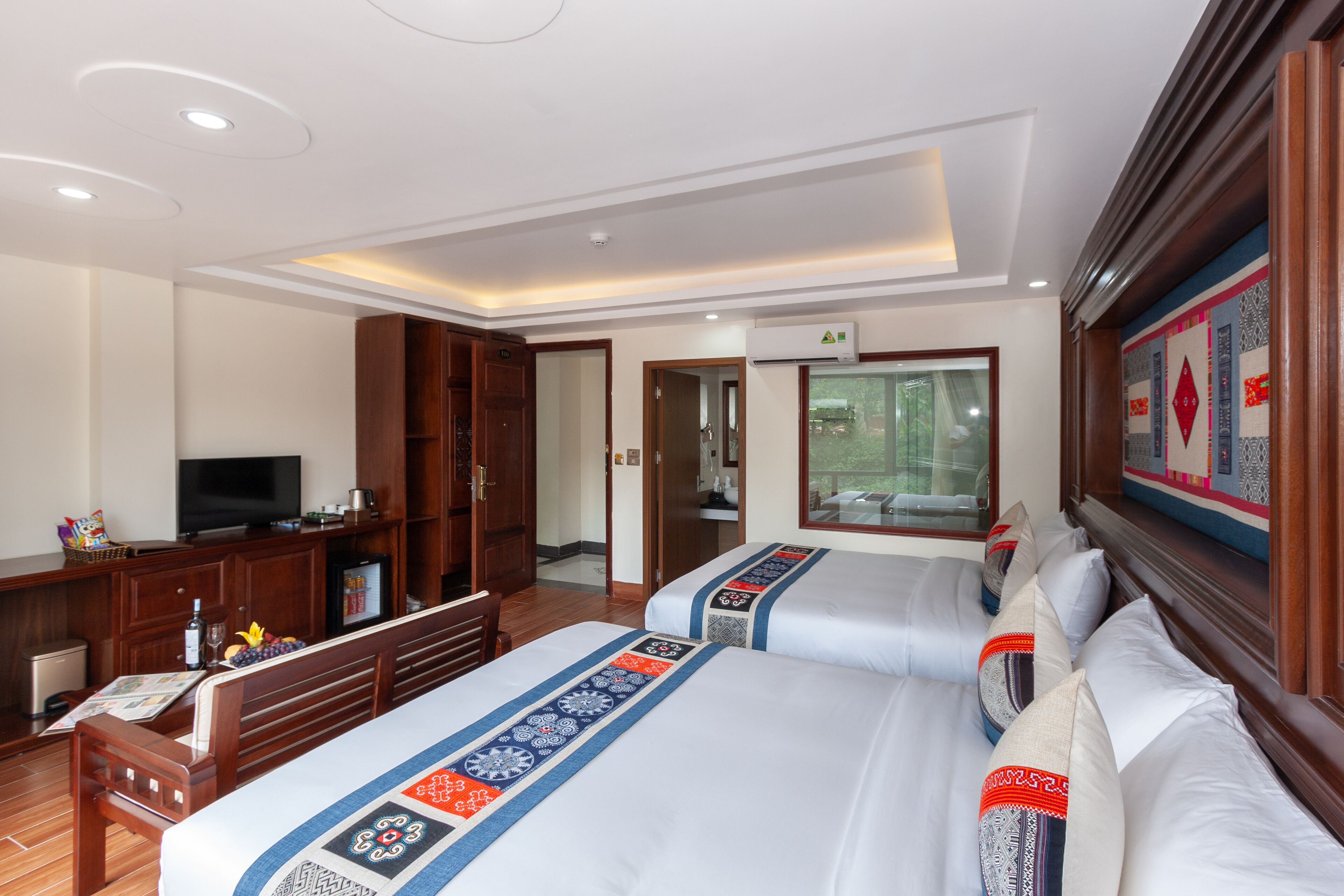 A hotel room with two beds, a television, a desk with a computer, and a wardrobe.