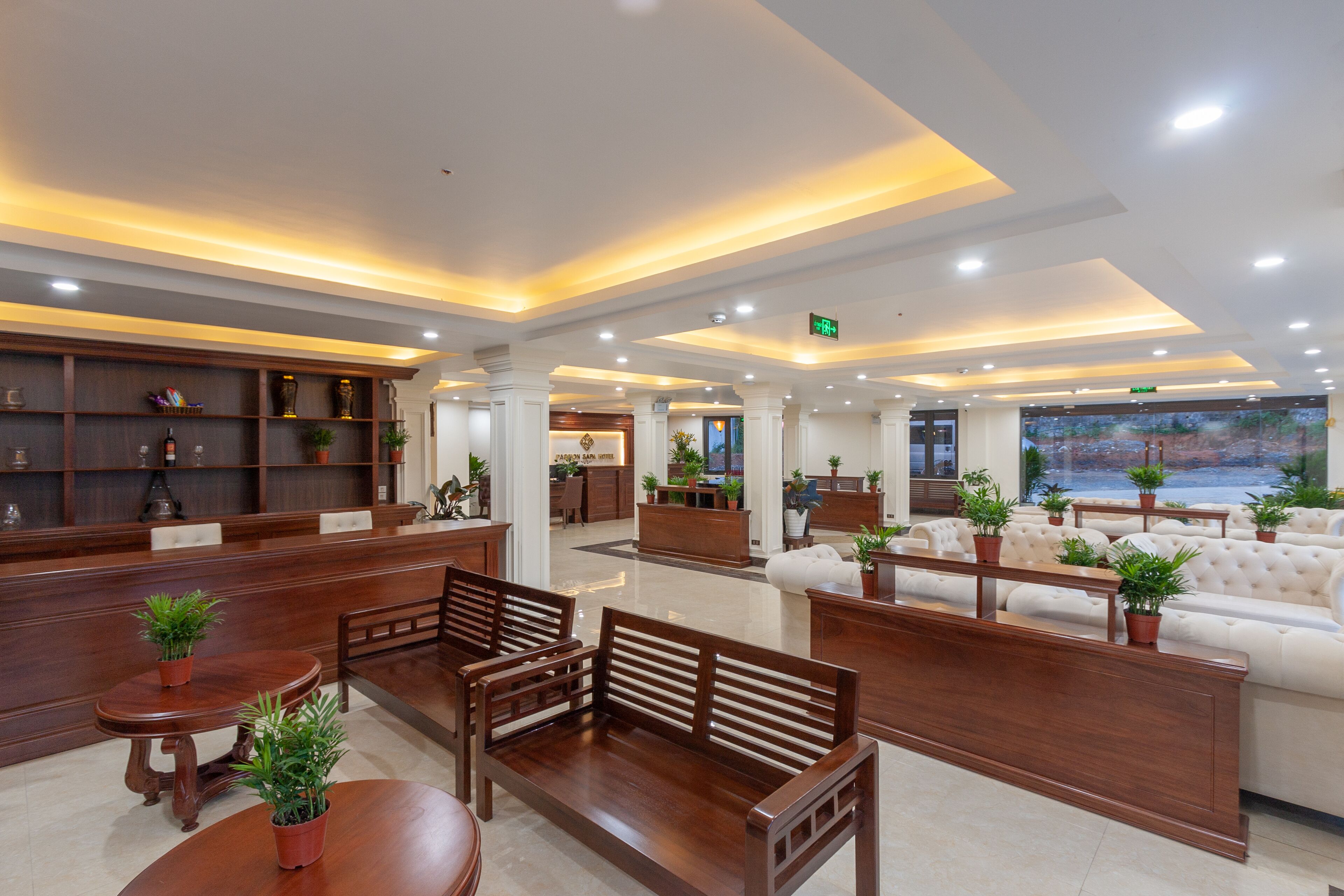 A spacious lobby with a reception desk, seating area, and a large window offering a view.