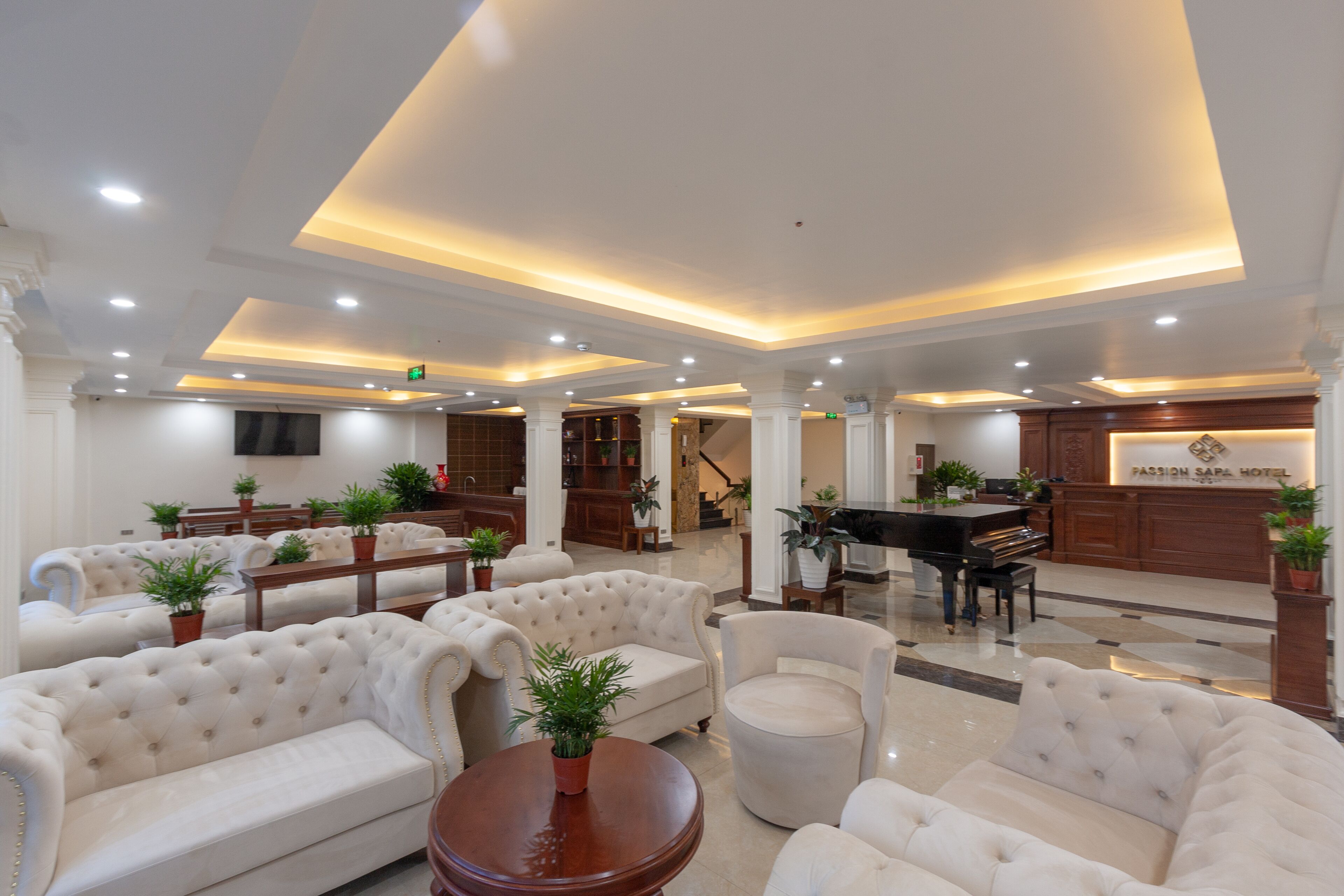 A spacious lobby with plush seating, a grand piano, and a reception desk.