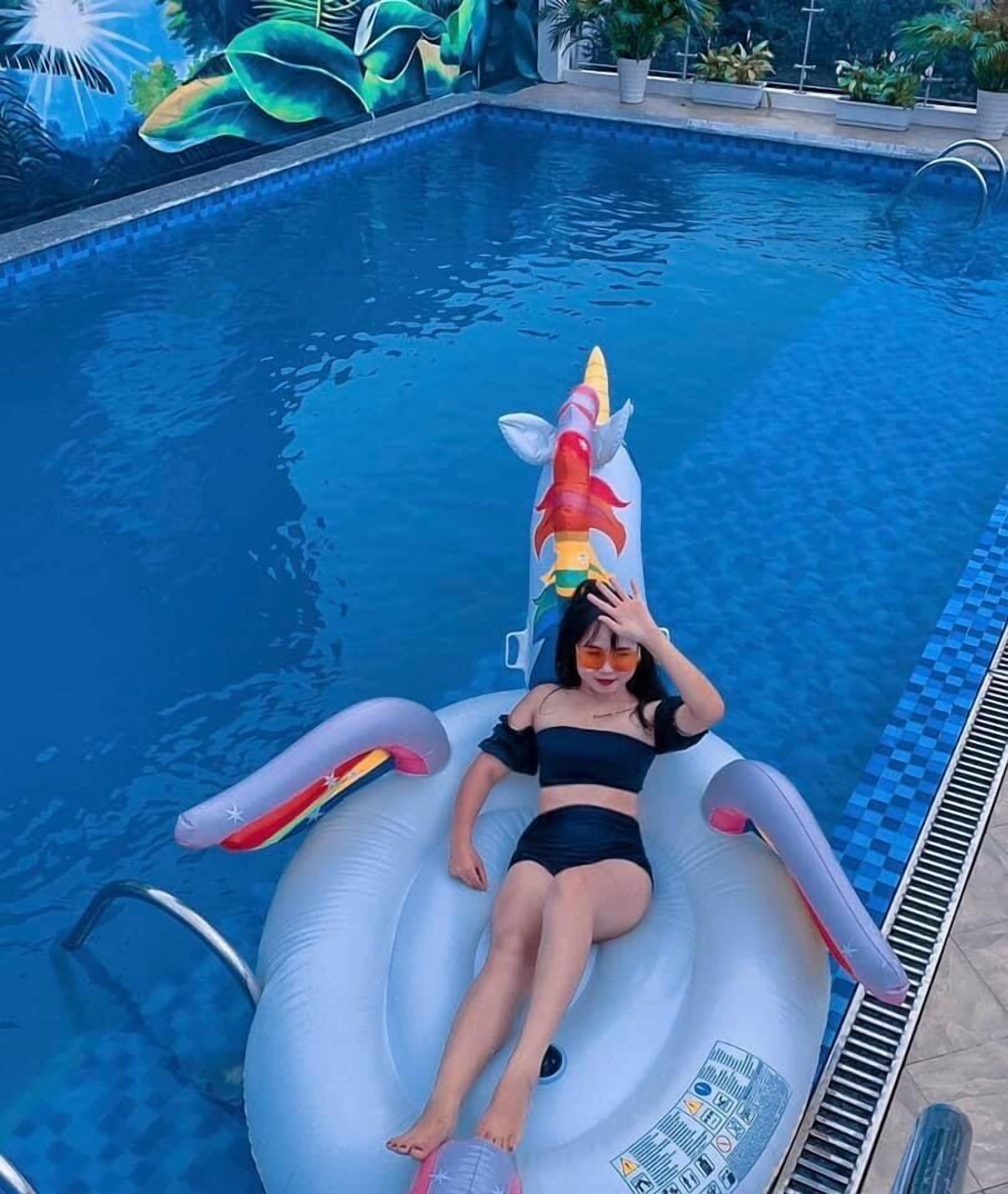 A person lying on an inflatable unicorn float in a swimming pool.