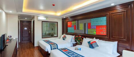 A hotel room with two beds, a wooden headboard, a desk with a computer, and a large window.