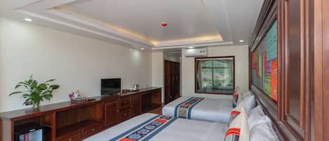 Habitación de hotel con dos camas, televisión, refrigerador pequeño y ventana con vistas.