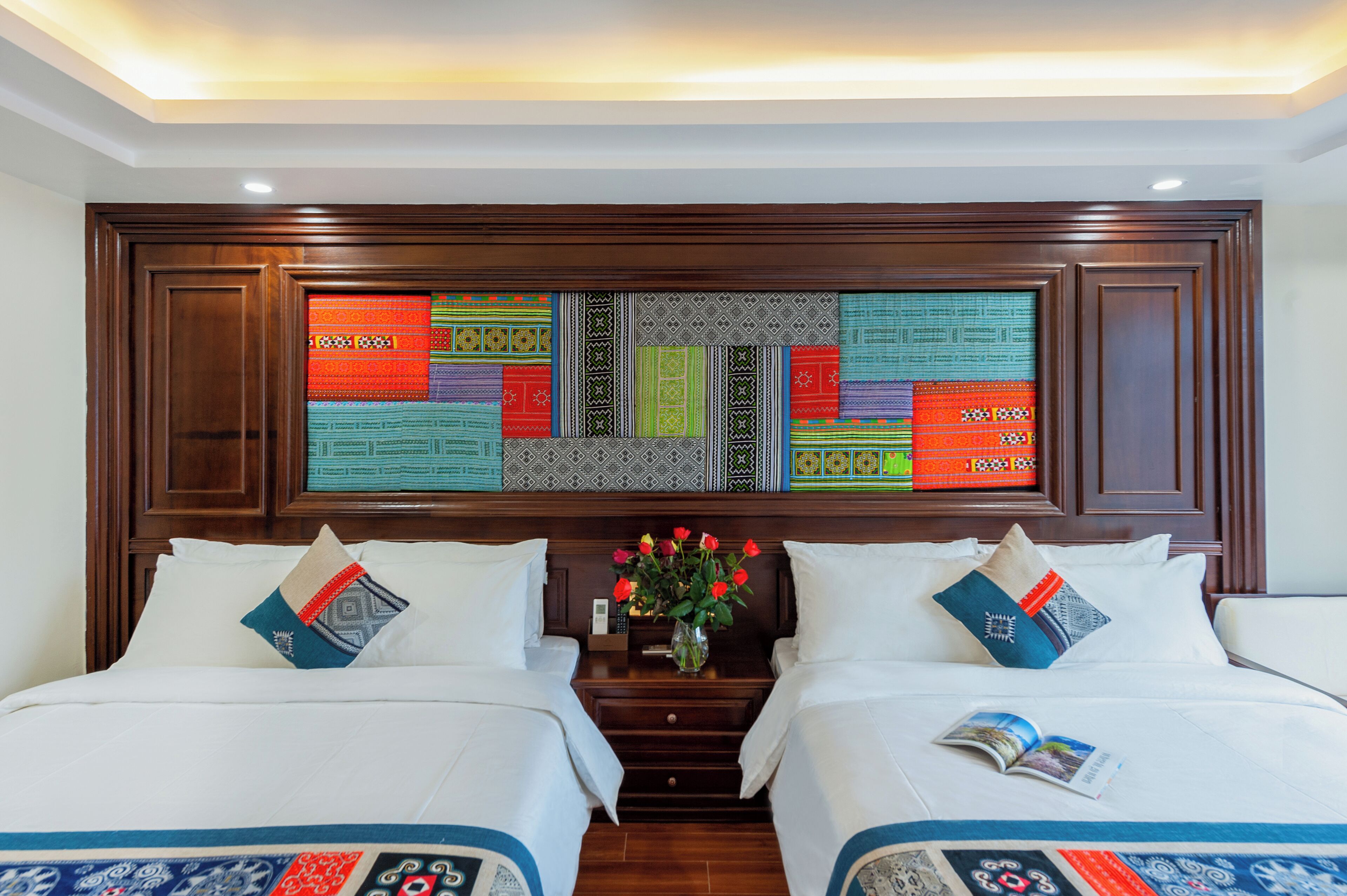 A hotel room with two beds, a wooden headboard, and a decorative wall panel.