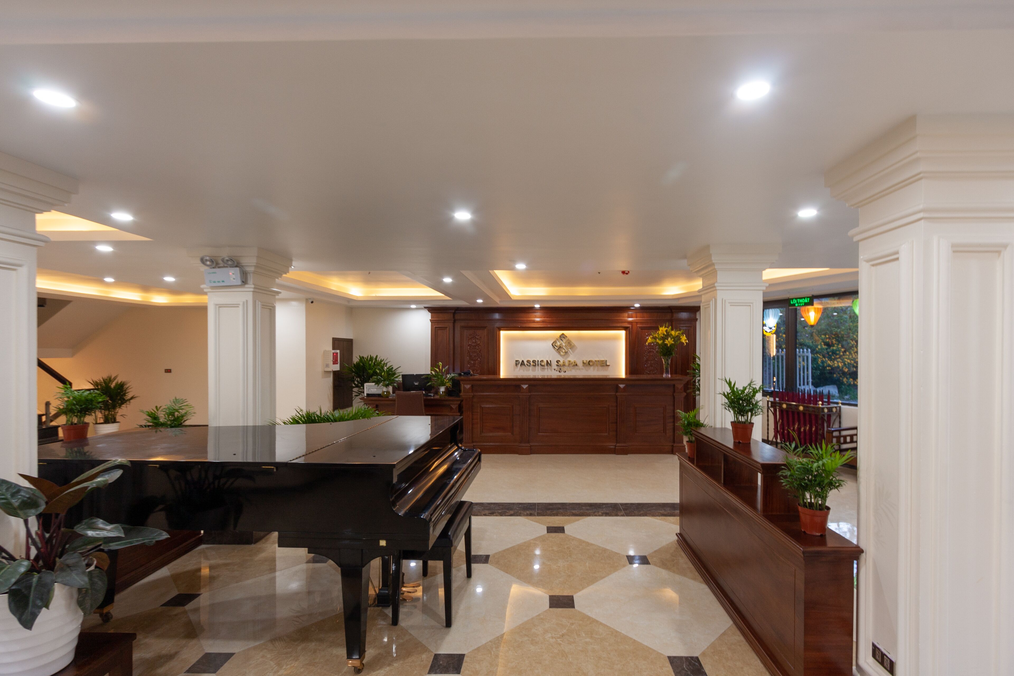 Un vestíbulo de hotel con un piano de cola, una recepción y plantas en macetas.