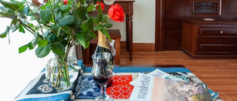 A table with a blue and white patterned tablecloth, a vase with roses, a wine glass, and a magazine titled 'Wanderlust'.