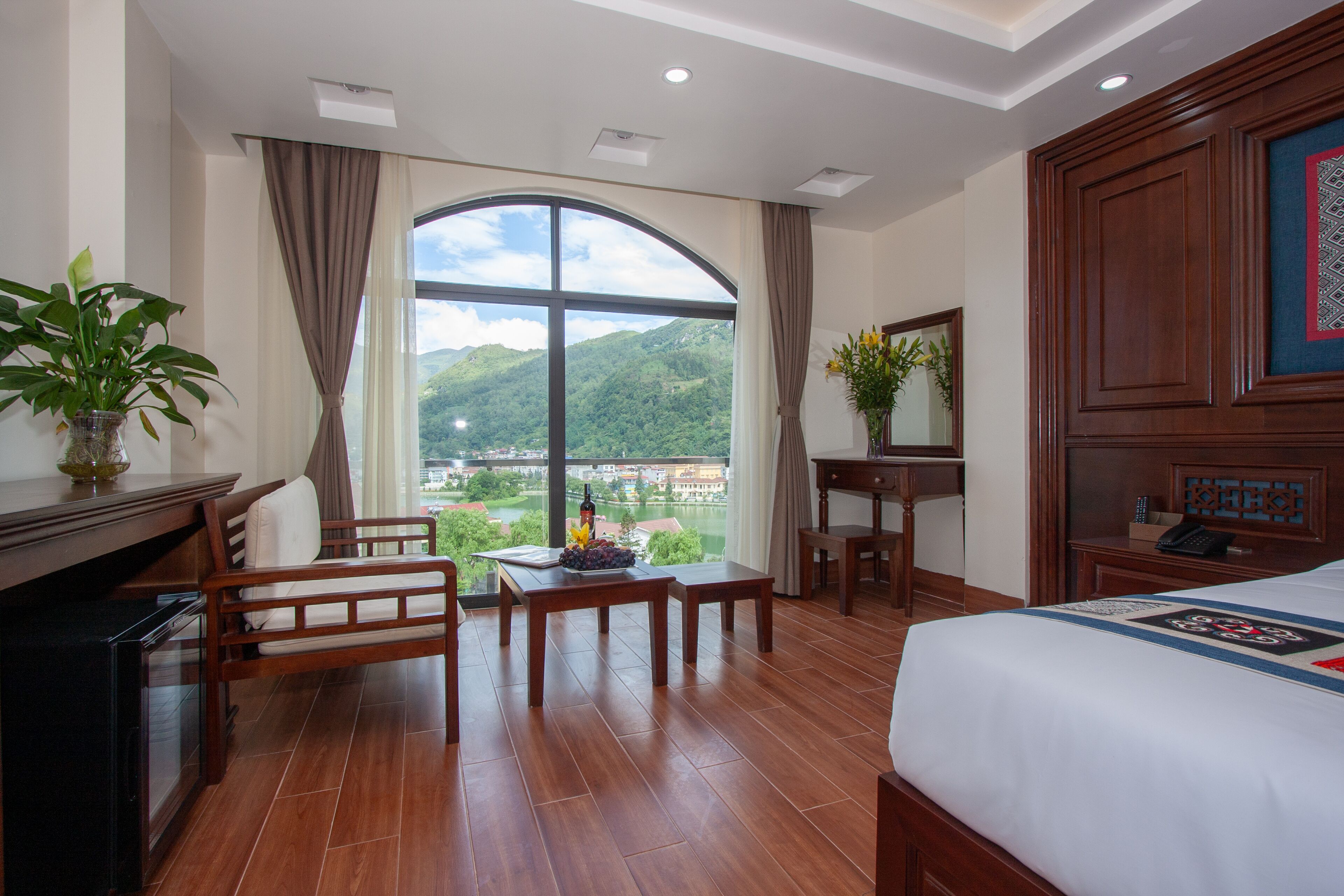 Une chambre d’hôtel avec une grande fenêtre, un lit, un bureau et une chaise.