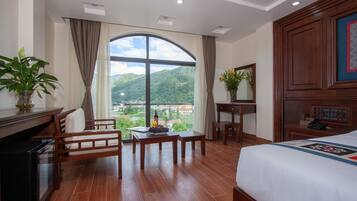A hotel room with a large window, a bed, a desk, and a chair.