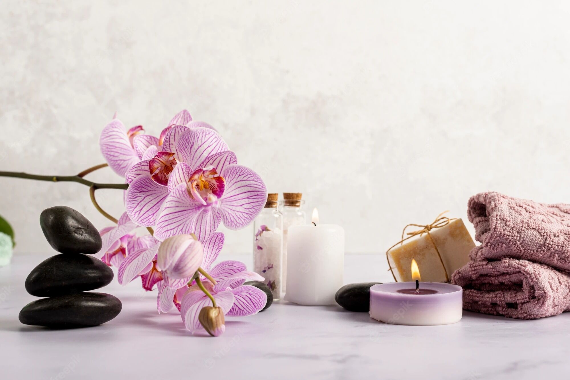 A spa setting with a flower arrangement, candles, and towels.